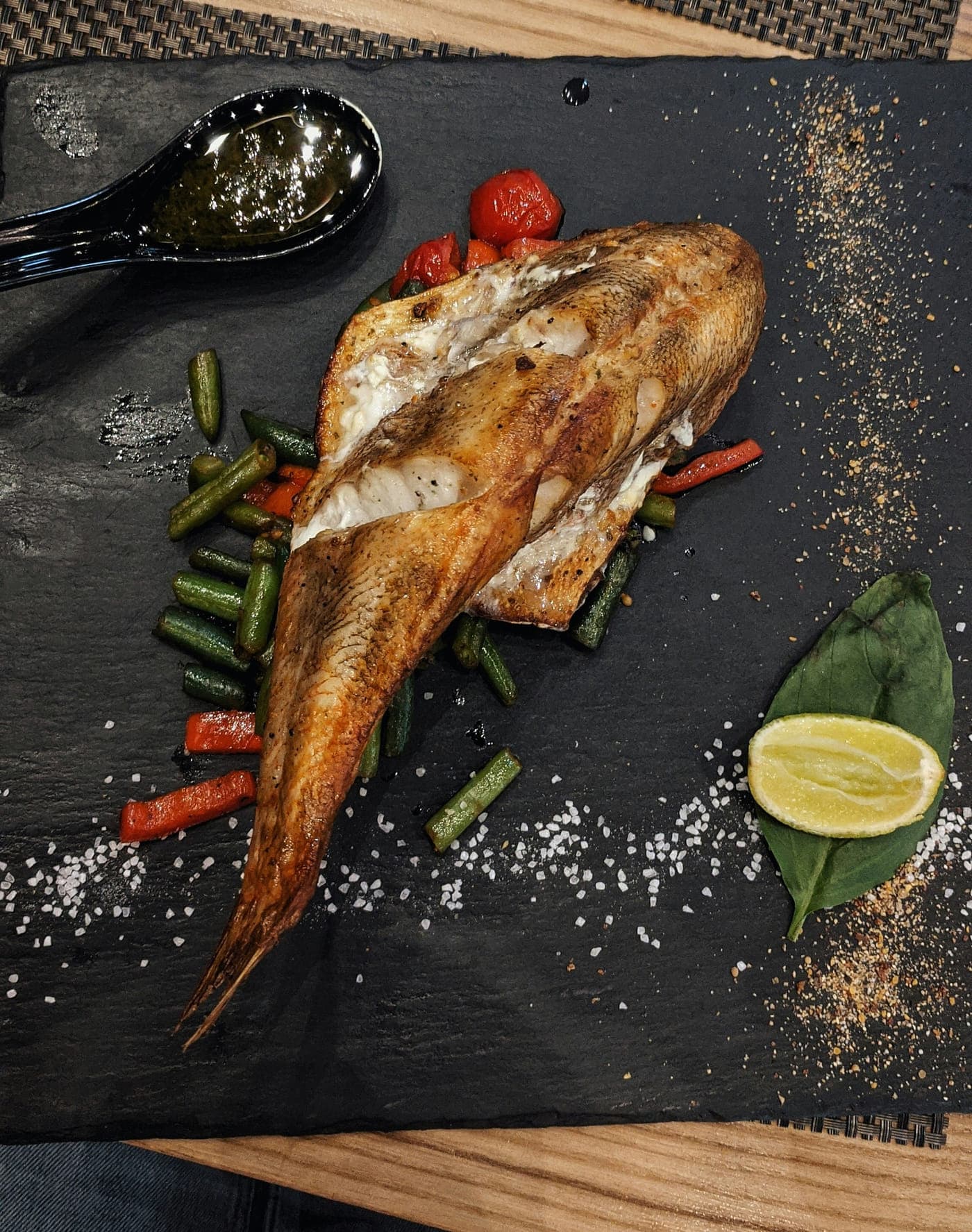 A whole grilled fish with lemon and charred vegetables