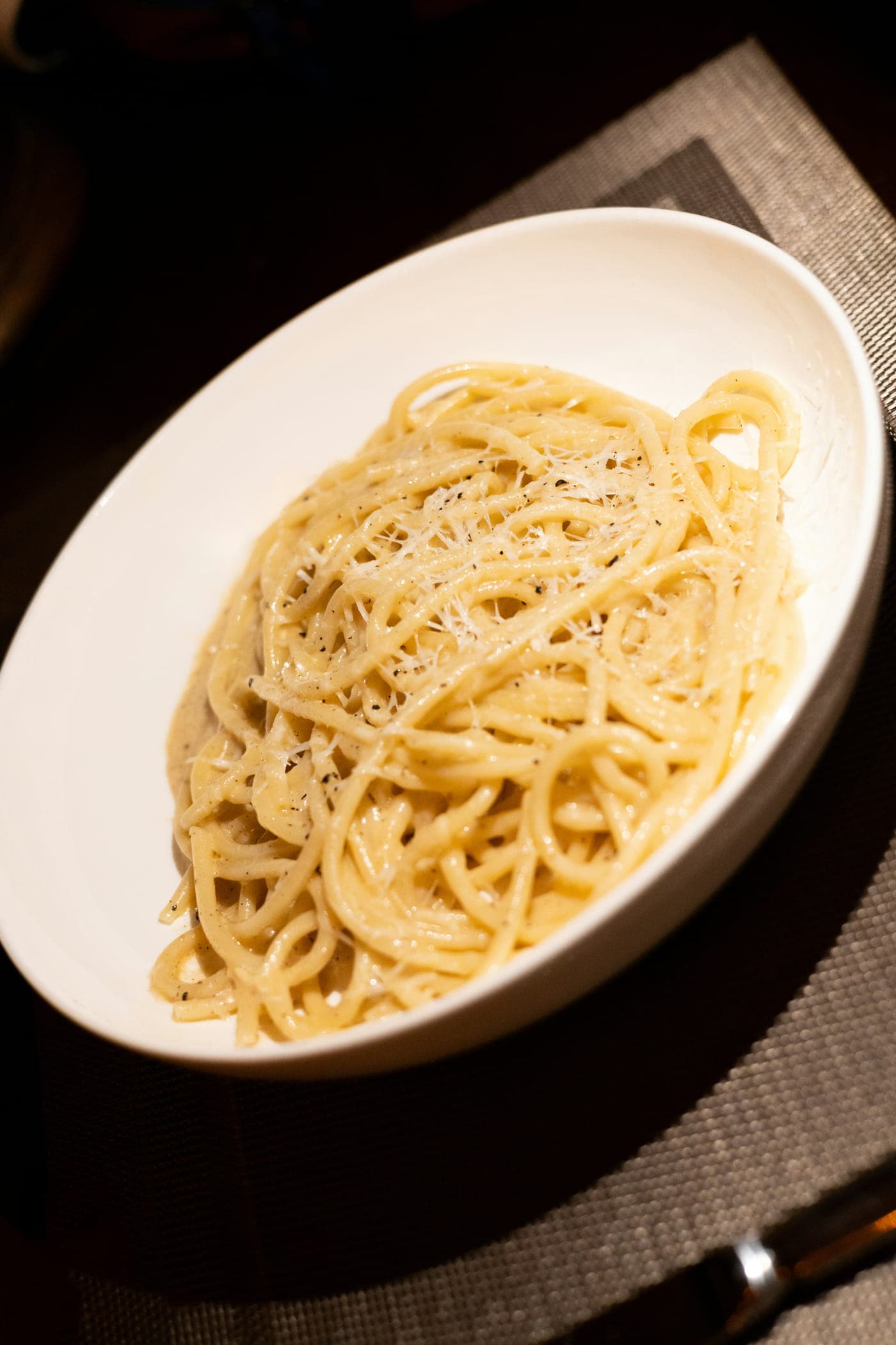 Tonnarelli tossed in pecorino, coiled in a shallow white bowl