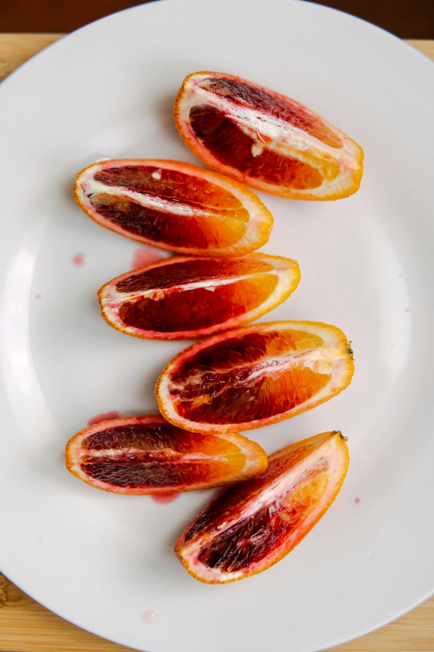 Wedges of blood orange fanned across a white plate
