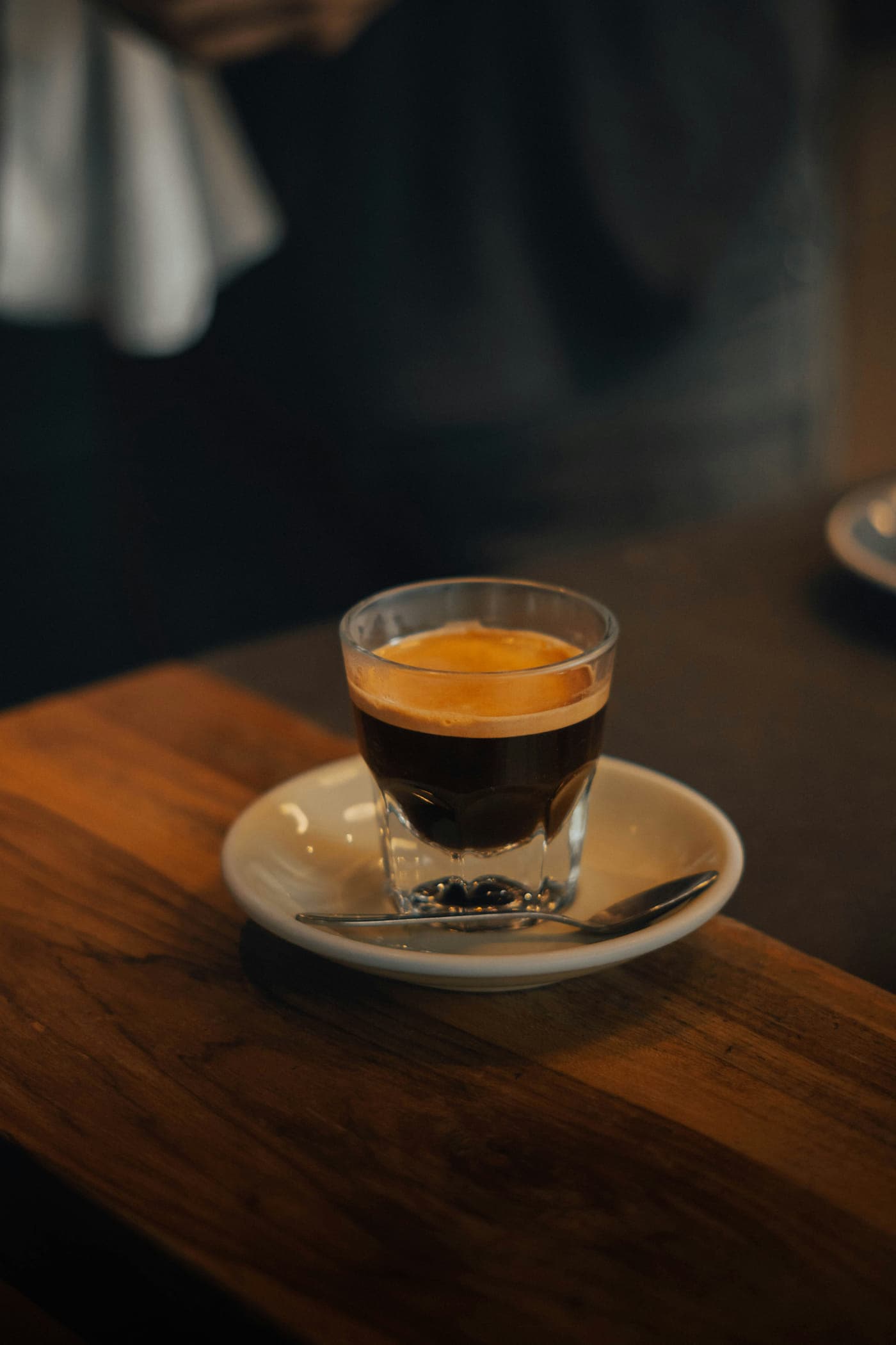 A glass of espresso with crema on a saucer