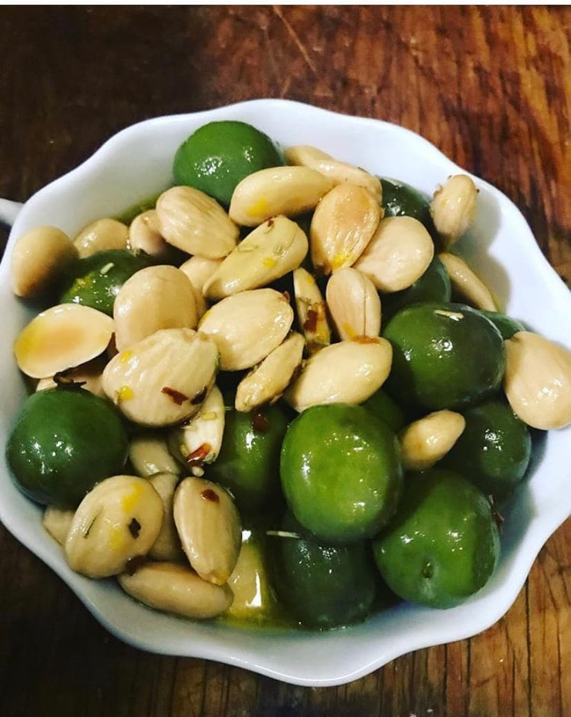 Green olives and blanched almonds in a small white bowl