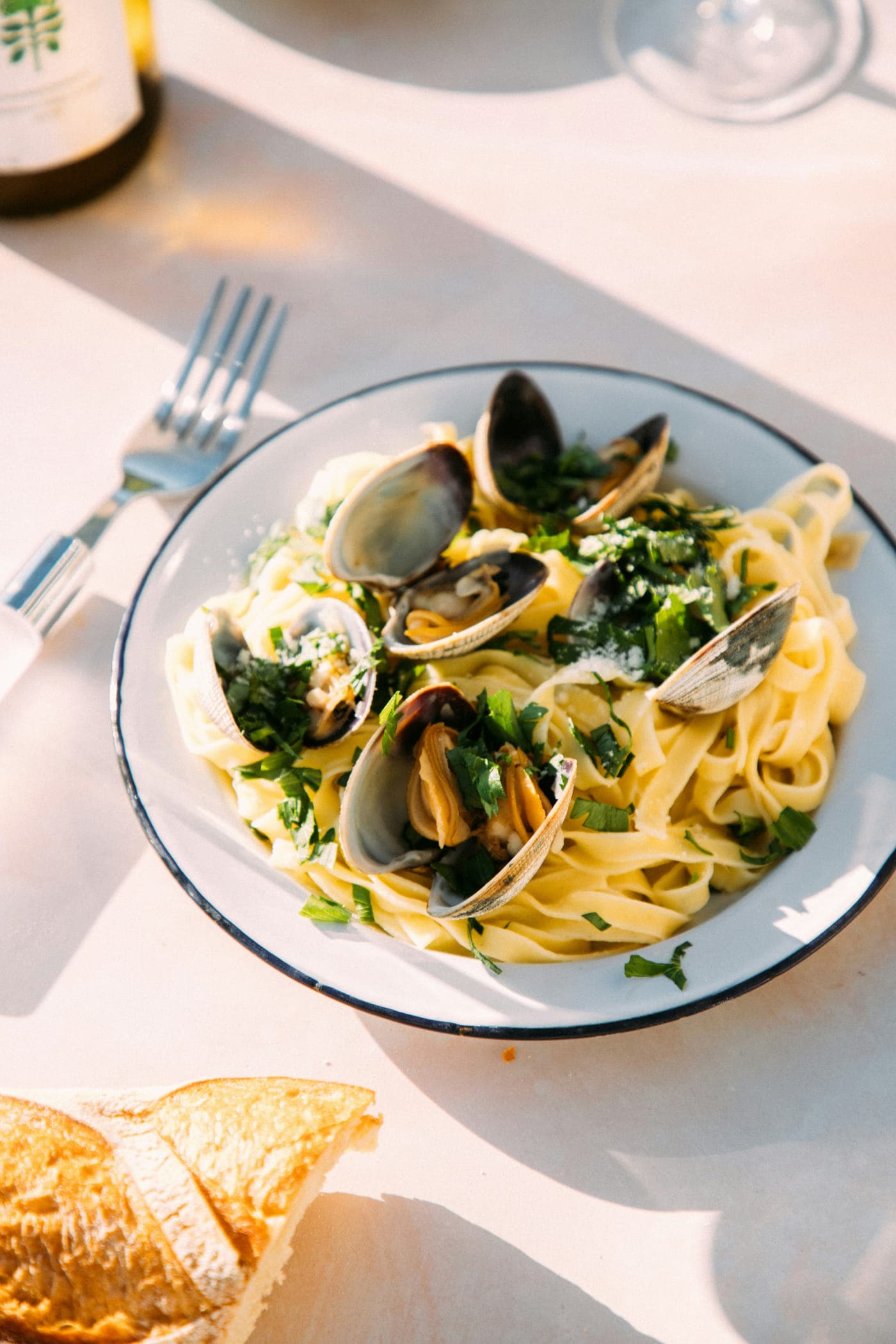 Tagliatelle and open clams with parsley on a rimmed plate